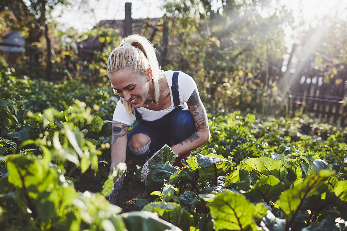 Woman crouched down in garden and smiling as she works