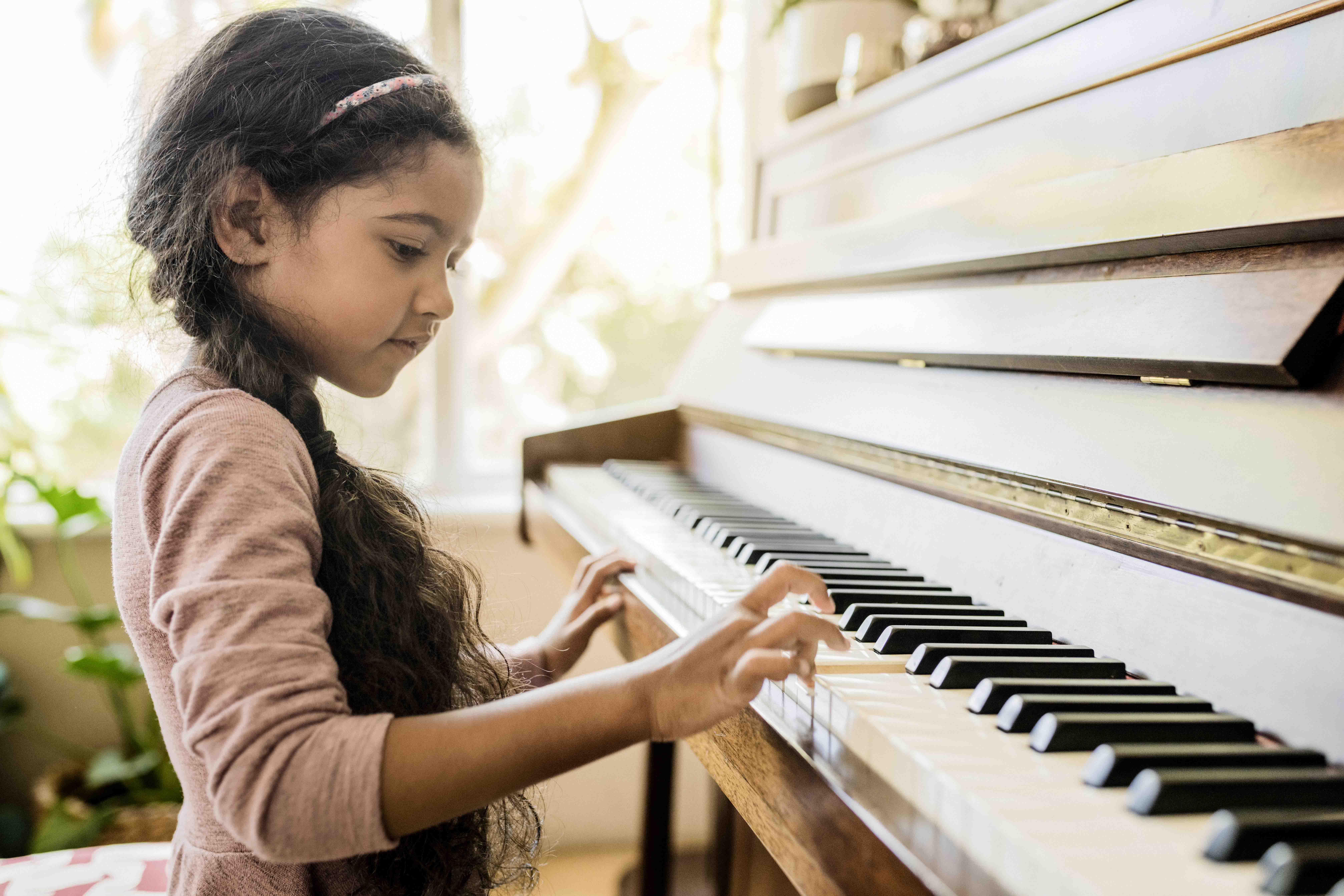 Side view of a young girl, about 6 or 7 years old, playing the piano